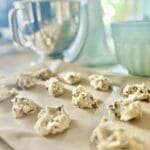 A close-up of chocolate chip cookie dough with visible chocolate chunks, resting on parchment paper, ready to be baked.