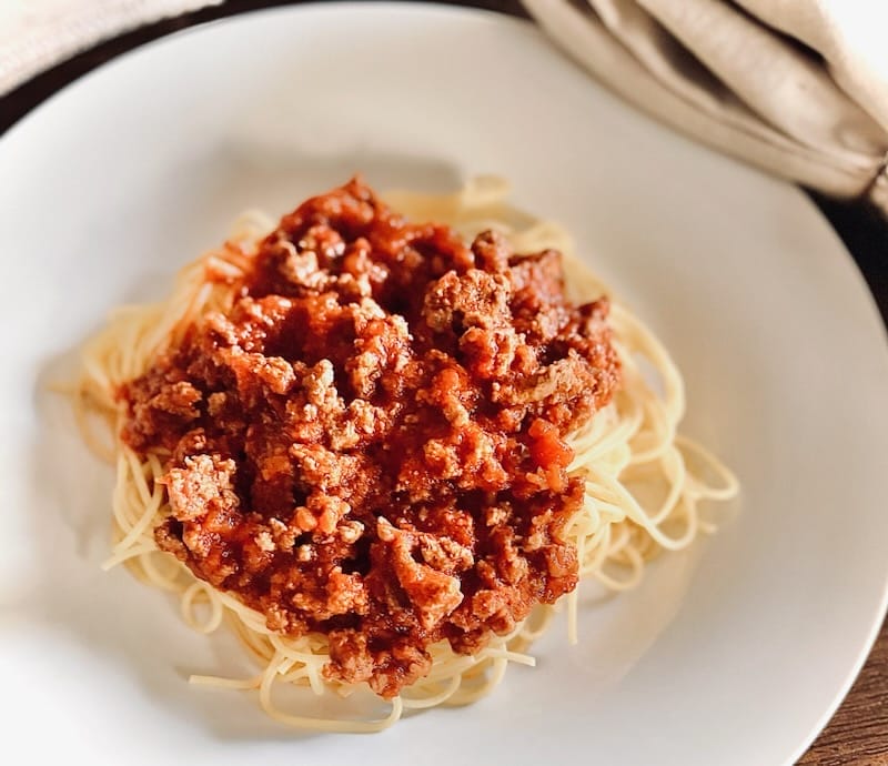 A neatly arranged display of Barilla thin spaghetti next to a jar of Rao’s Homemade Marinara Sauce, highlighting the key ingredients for a simple and delicious spaghetti dish.