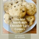 A plate of warm, freshly baked sourdough chocolate chip cookies, topped with a sprinkle of sea salt, accompanied by a glass of cold milk.